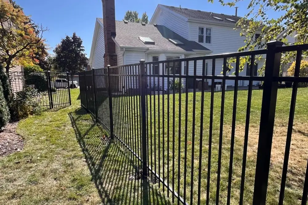 Black aluminum ornamental fence running along a sloped yard