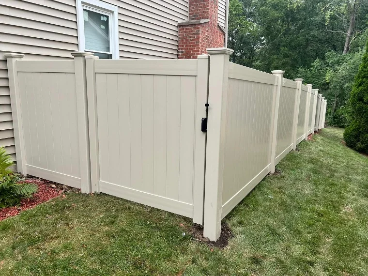 Tan vinyl privacy fence installed on a residential lot